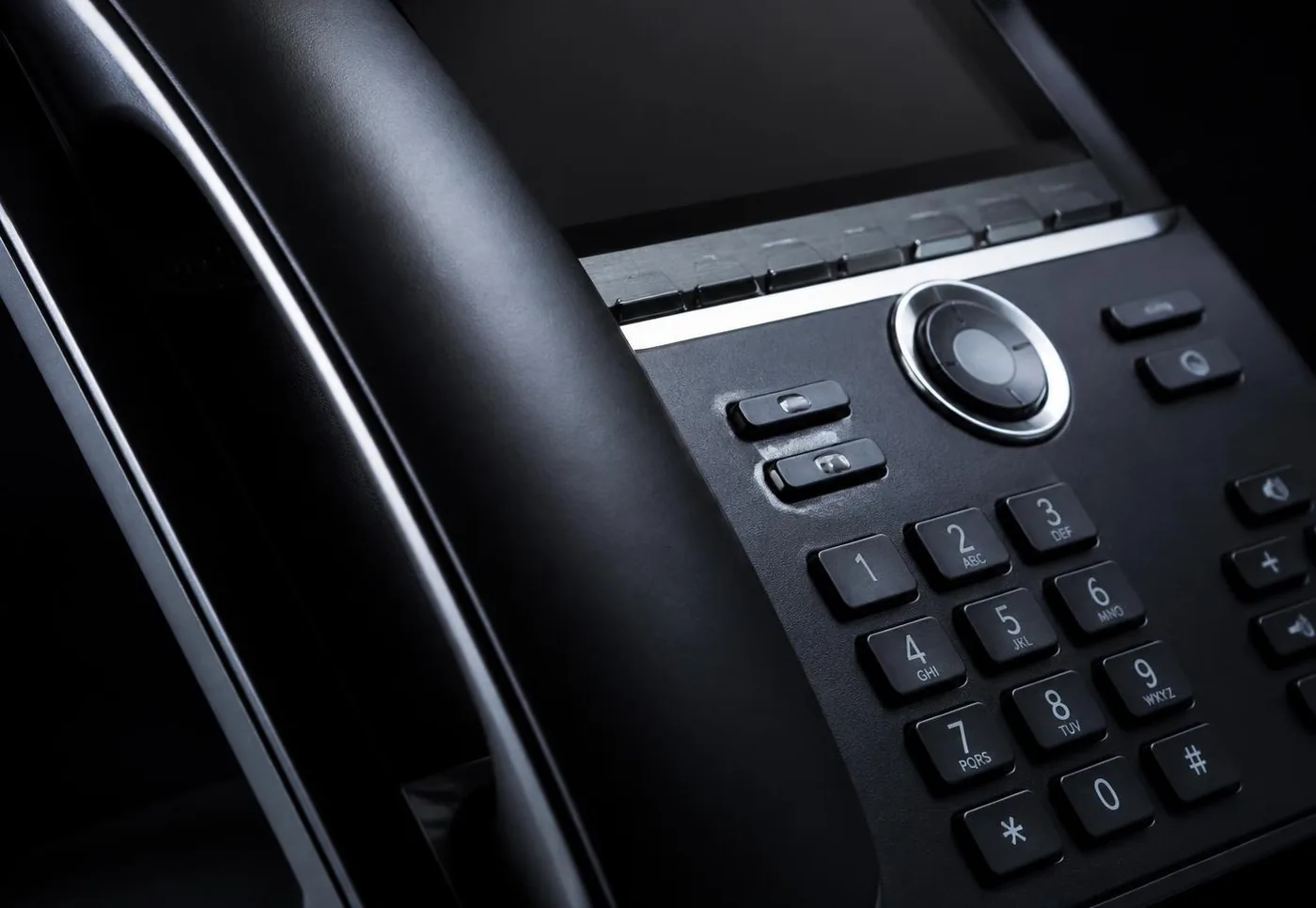 Combiné et clavier de téléphone IP noir en gros plan avec des reflets froids
